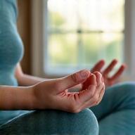 Person calmly meditating with hands in mudra pose, bathed in soft light.